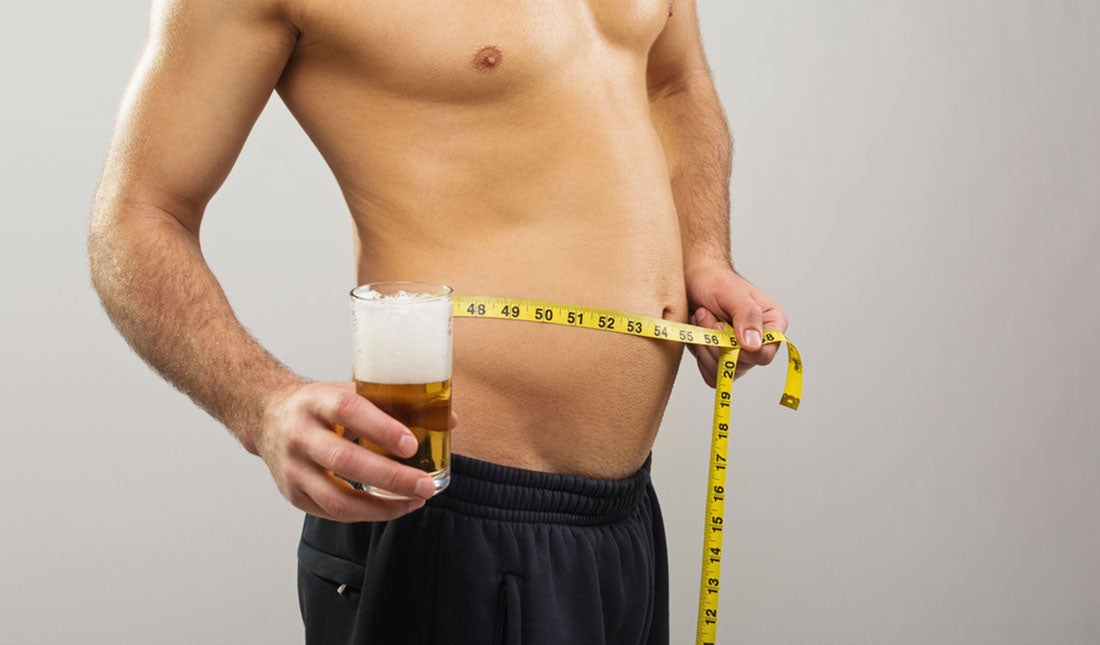 holding tape measure around belly with beer