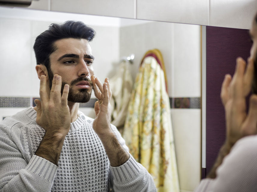 man applying facial moisturizer