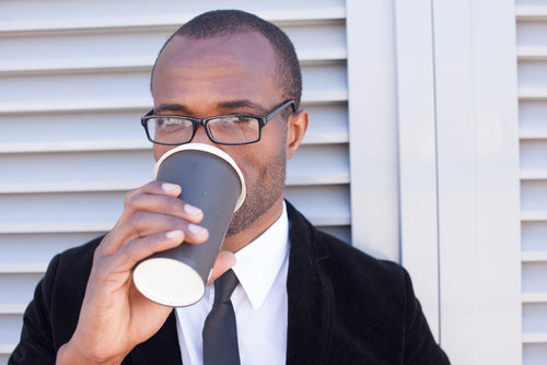 man drinking coffee outside office