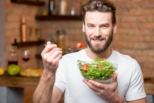 man eating salad with whole tomatoes