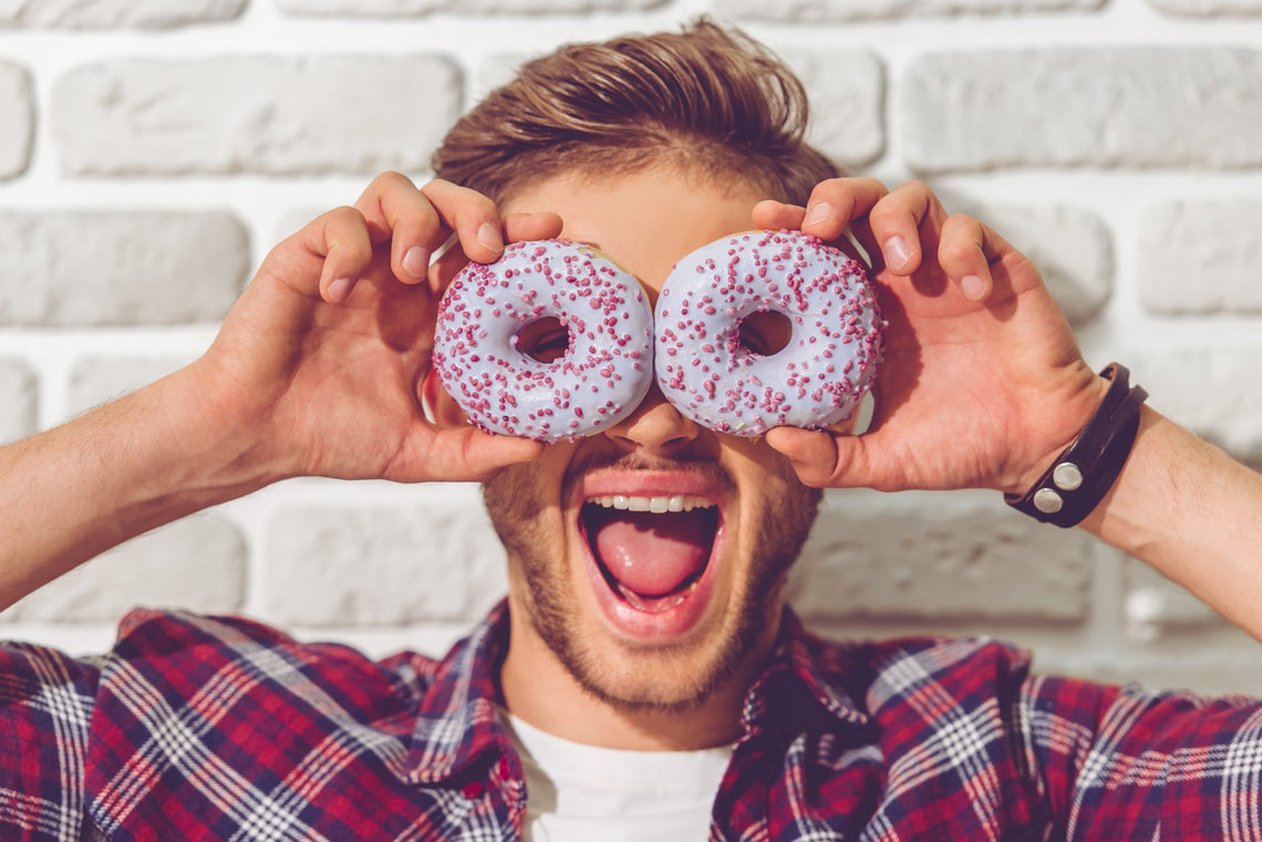 Man holding to sprinkle doughnuts over his eyes