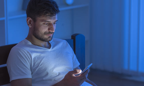man sitting in bed with phone
