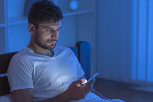 man sitting in bed with phone