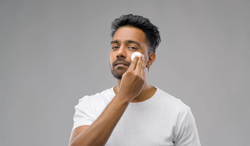 man toning face with cotton pad